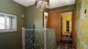 Un pasillo con una puerta de madera, un radiador y una ventana con persianas.