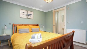 Een slaapkamer met een bed, een nachtkastje, een lamp en een deur naar een badkamer.