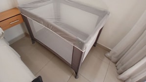Una habitación con cama, mesita de noche, una pequeña mesa y una ventana con cortinas.