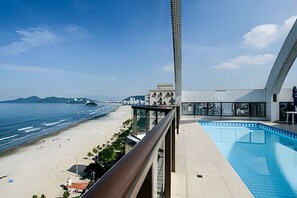 A modern hotel with a pool, beach view, and a tall building in the background. - SHB - Apê Retrô - Beira-Mar (Santos)