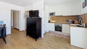 A modern kitchen with white cabinets, a wooden countertop, and a black entertainment unit. - BONREPOS 2 Roses / Roses - INTERimmo (Rosas / Roses)