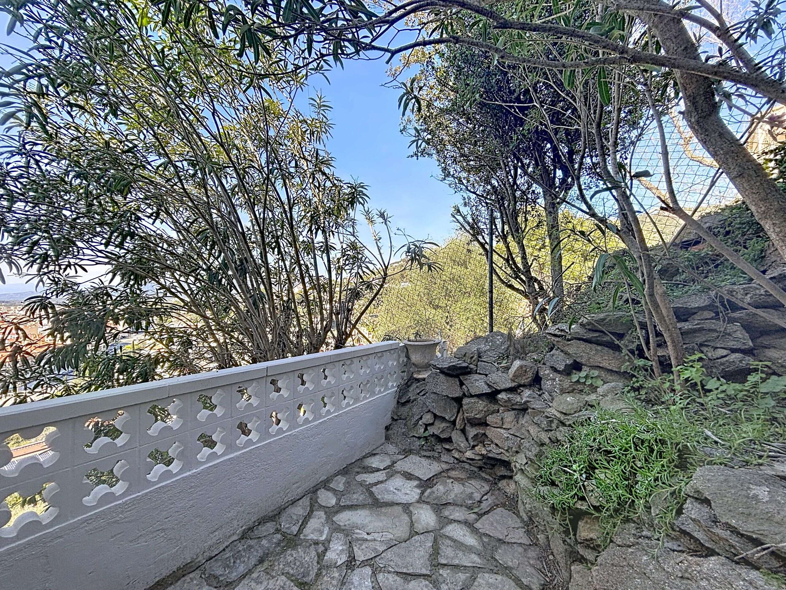 A stone pathway leading to a stone wall with a decorative railing.
