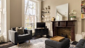 A living room with a fireplace, a television, and a bookshelf. - Punk Hip Plush 1-bed in Camden Town (London)