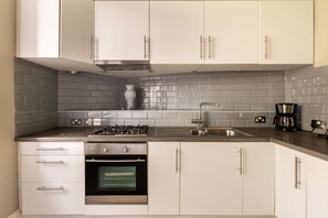 Een moderne keuken met witte kastjes, een roestvrijstalen fornuis en een inbouwoven.