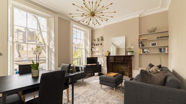 A modern living room with a fireplace, a dining area, and a bookshelf. - Punk Hip Plush 1-bed in Camden Town (London)