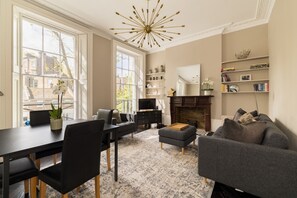 A modern living room with a fireplace, a dining area, and a bookshelf. - Punk Hip Plush 1-bed in Camden Town (London)