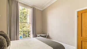 A hotel room with a bed, a small table, and a window with curtains. - Punk Hip Plush 1-bed in Camden Town (London)