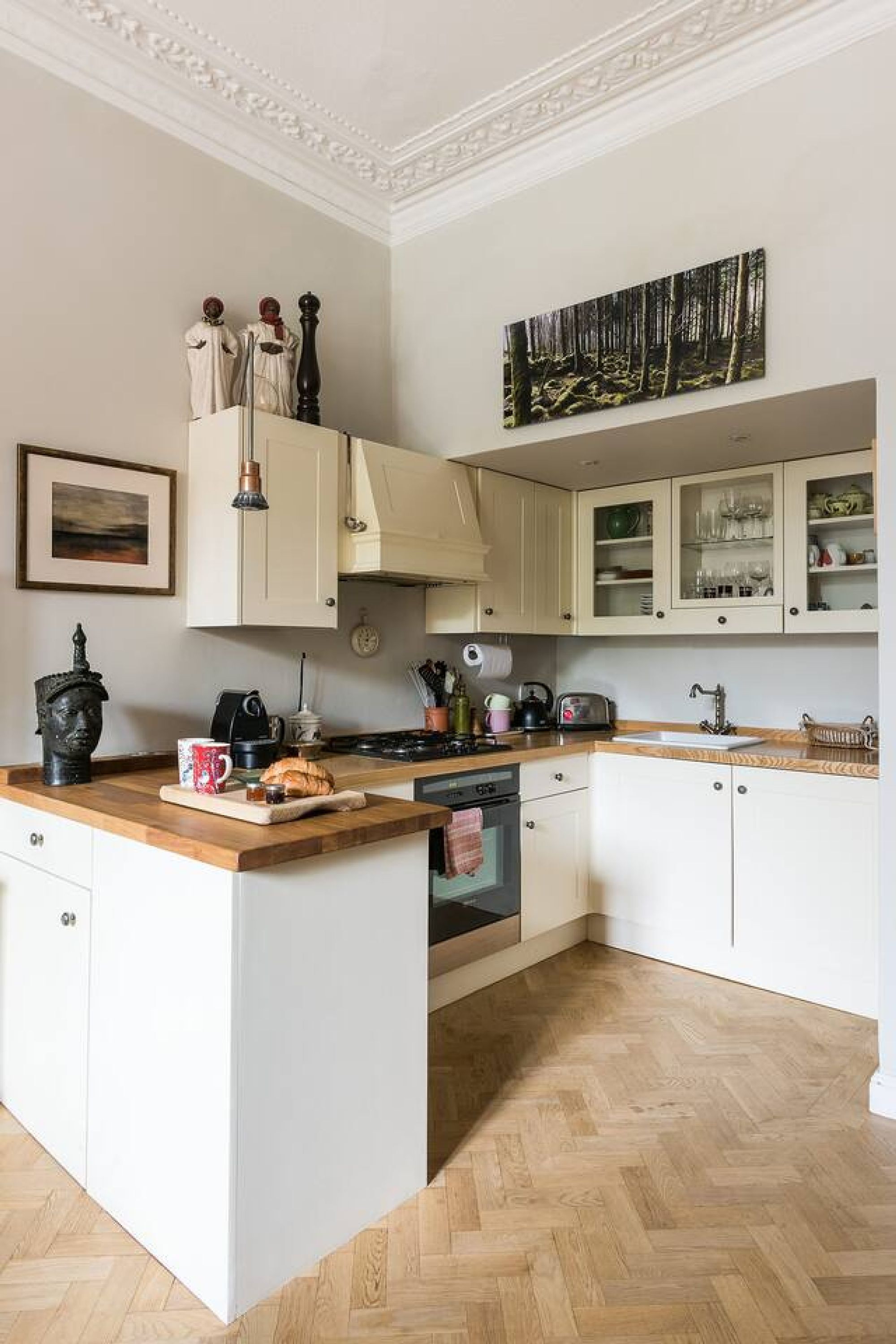 A kitchen with white cabinets, a wooden countertop, a stove, and a sink.