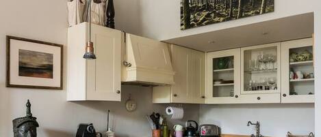 A kitchen with white cabinets, a wooden countertop, a stove, and a sink.