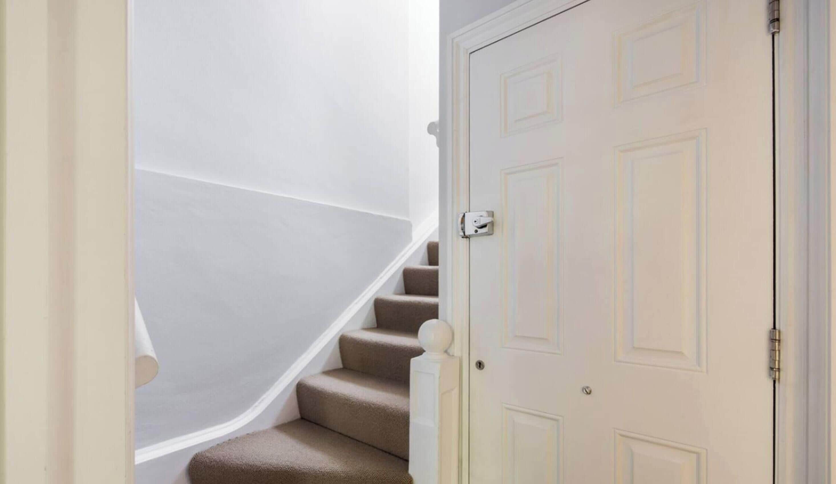 A white door with a traditional design, a carpeted staircase, and a white wall.