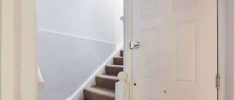 A white door with a traditional design, a carpeted staircase, and a white wall.