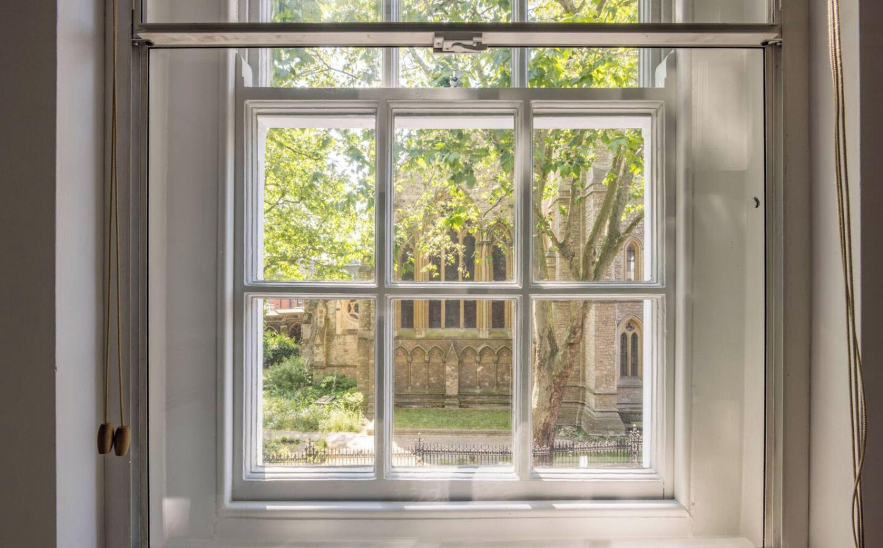 Una ventana con vista a un edificio con arcos y árboles.