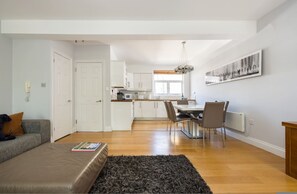Eine moderne Wohnung mit Wohnzimmer, Küche, Essbereich und einem großen Fenster.