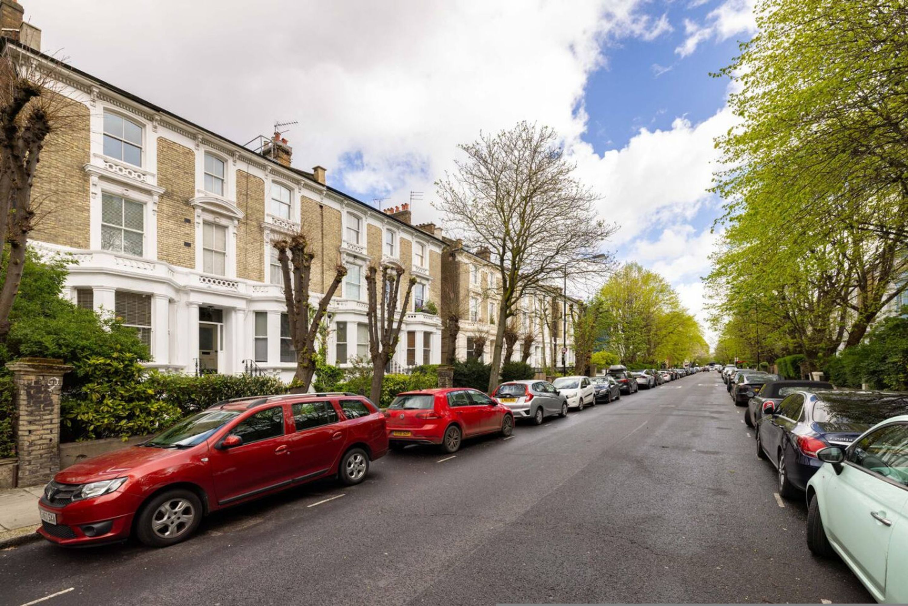 A row of terraced houses with parked cars on the street.