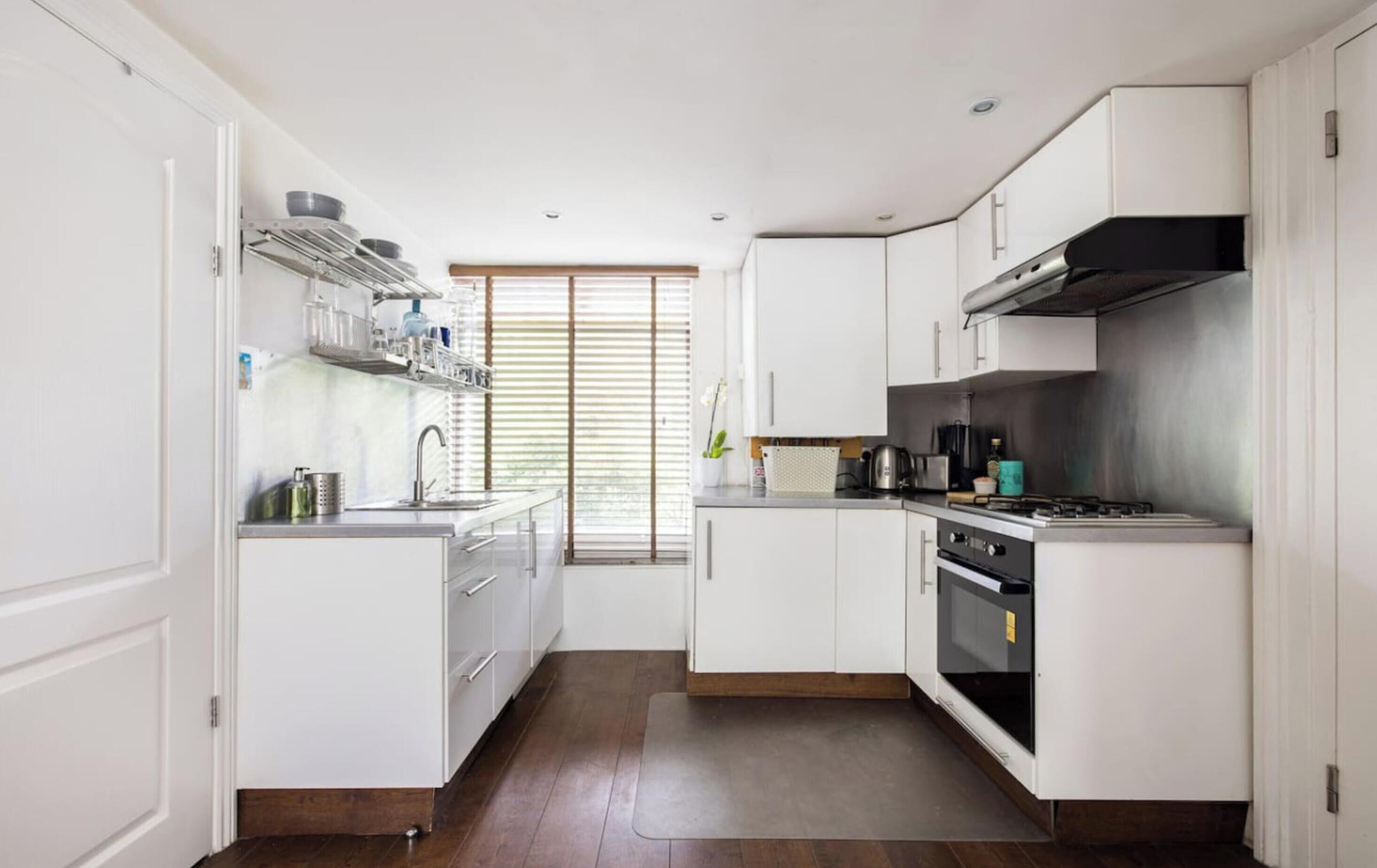 Una cucina moderna con mobili bianchi, una cappa in acciaio inossidabile e un forno integrato.