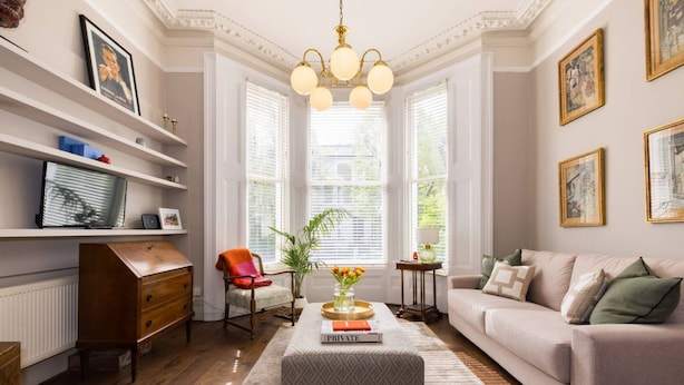A well-lit living room with a sofa, a coffee table, and a bookshelf. - Victorian Blush 1BR Near Portobello Notting Hill (London)