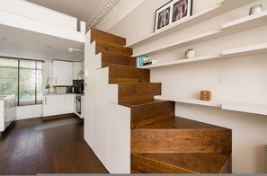 Eine moderne Küche mit weißen Schränken, einer Holztreppe und eingebauten Regalen mit Dekorationselementen.