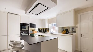 Une cuisine moderne dotée d’un îlot central, d’appareils électroménagers intégrés et d’un design minimaliste.
