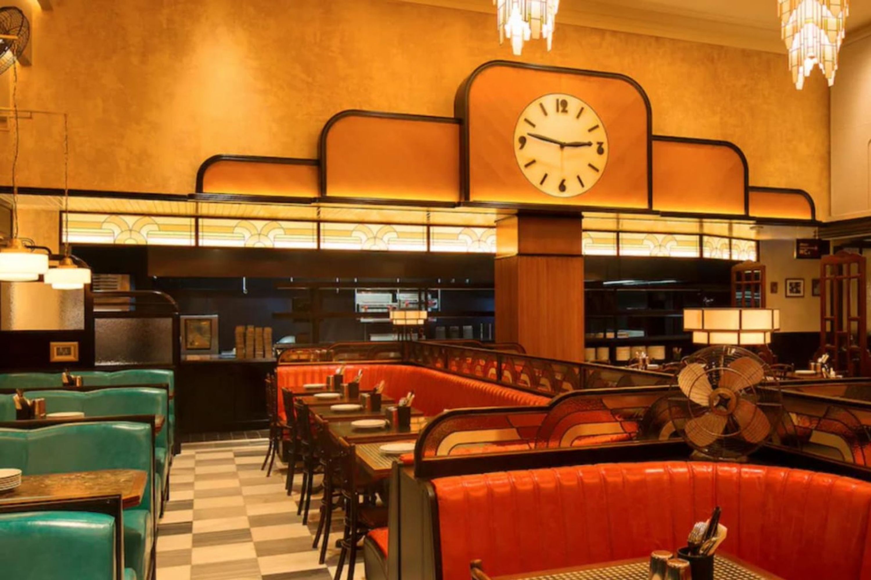 A retro-style restaurant interior with booths, a large wall clock, and classic decor.