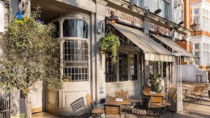 A corner building with outdoor seating, a sign reading 'The Champion,' and a hanging plant. - The Bengal Tiger 2 BR With Patio in Notting Hill (London)