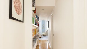 Ein Flur mit Bücherregalen, einem gerahmten Kunstwerk und einer Tür zu einem Zimmer.