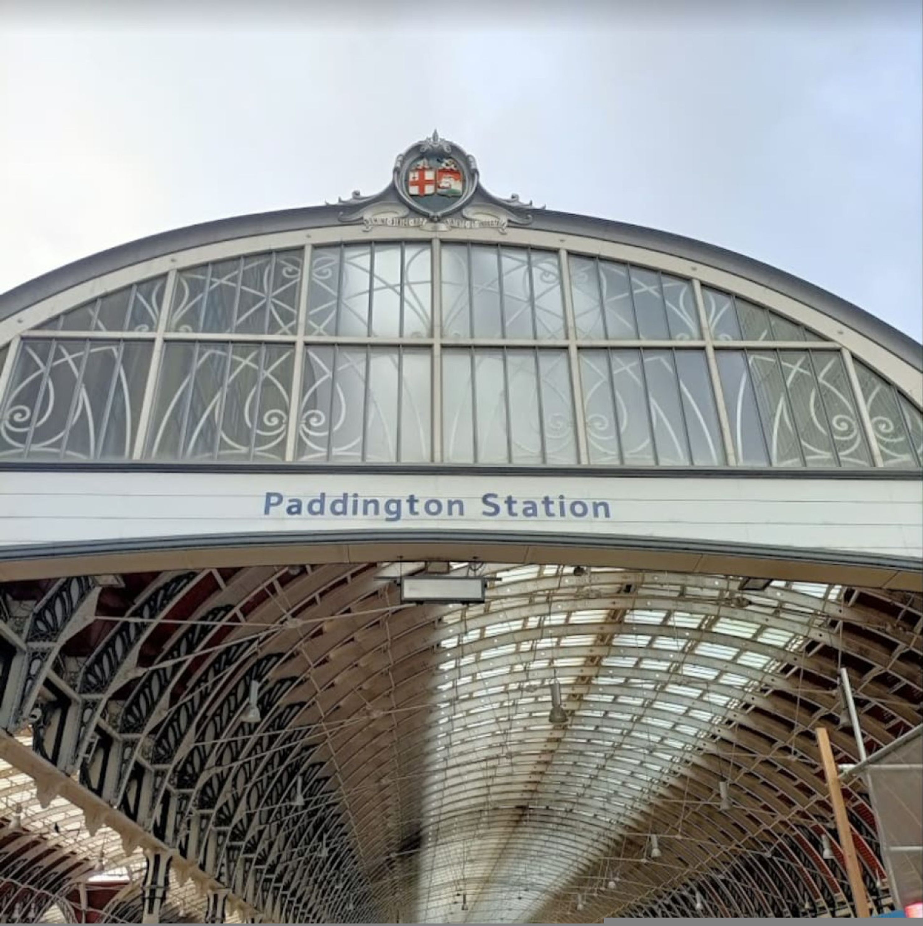 Paddington Station's arched roof with intricate metalwork and a crest at the top.