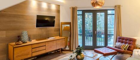 A modern living room with a wooden cabinet, a flat-screen TV, a sofa, and a coffee table.