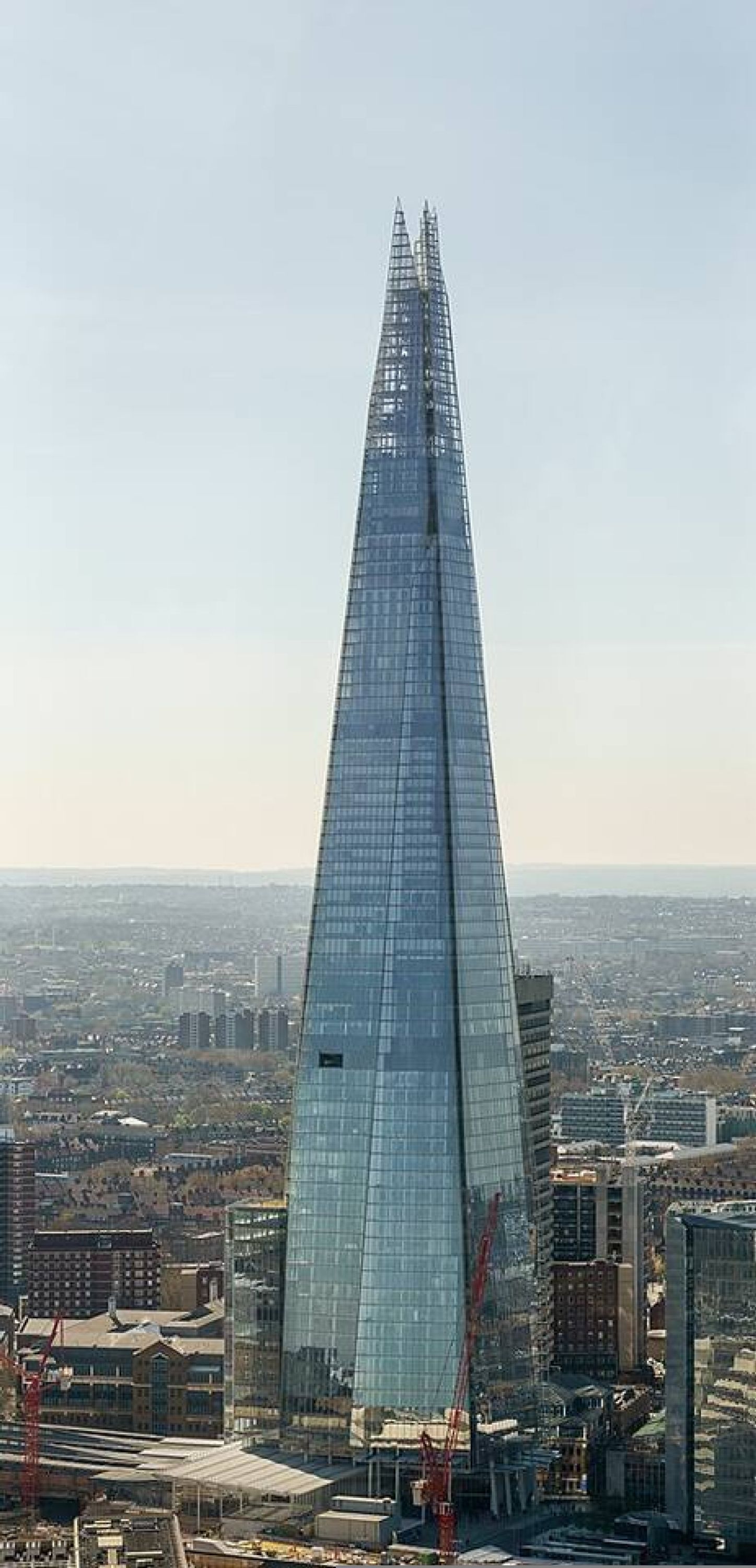 A tall, modern skyscraper with a pointed top, surrounded by a cityscape.