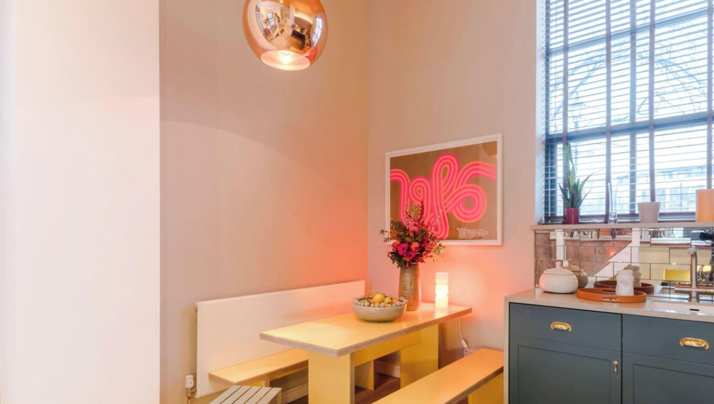 A modern kitchen with a dining area, a large window, and a neon sign.