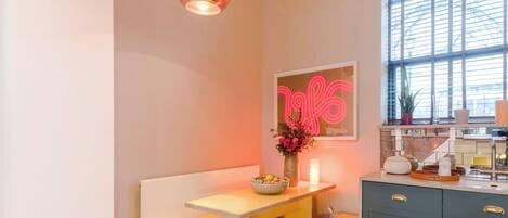 A modern kitchen with a dining area, a large window, and a neon sign.