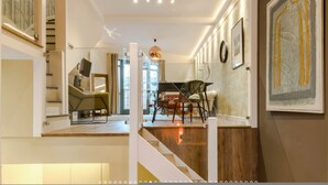 A modern interior with a staircase, a dining area, and artwork on the walls. - Neon Melody Playful 2 Bedrooms by London Bridge (London)
