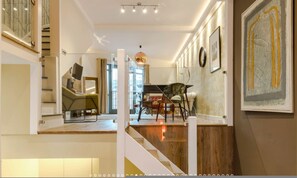 A modern interior with a staircase, a dining area, and artwork on the walls. - Neon Melody Playful 2 Bedrooms by London Bridge (London)