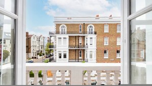 A view from a balcony of a multi-story building with white railings, a brick facade, and a clear sky. - Green Leafy 2 Bedroom in Clapham (London)