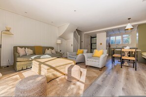 Ein geräumiger Wohnbereich mit einer Couch, Sesseln, einem Couchtisch und einem Teppich.