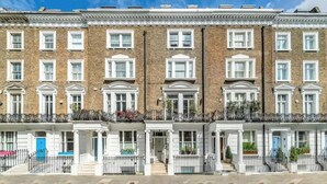 A row of terraced houses with uniform brickwork, white window frames, and black metal railings. - Cosy and Stylish Chelsea 2 Bedroom Flat (London)