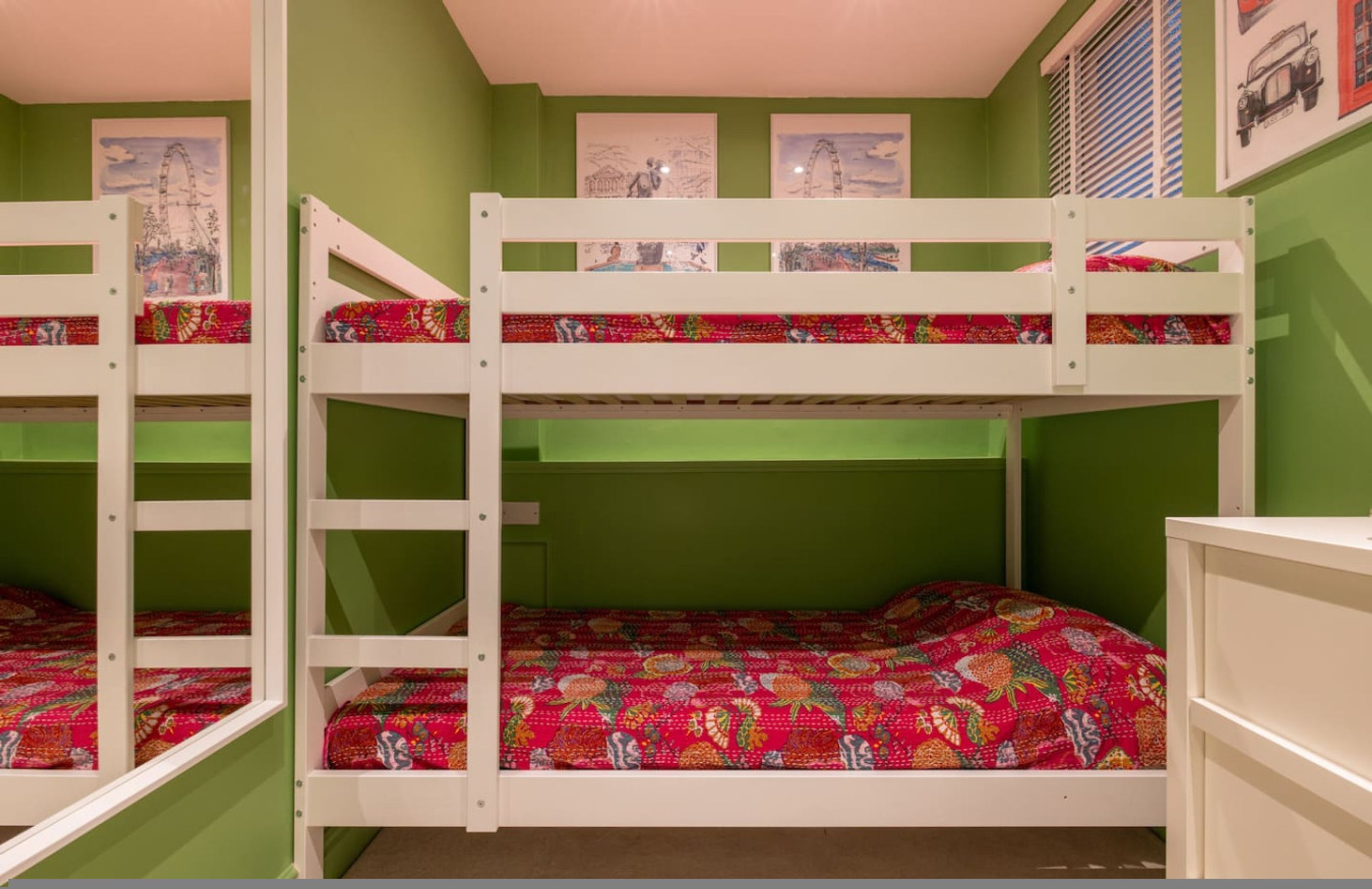A bunk bed room with green walls and artwork on the walls.