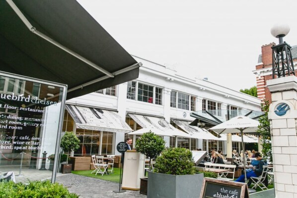 Ein Gebäude mit einem Café und einer Außenbestuhlung.