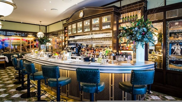 A bar area with a counter, stools, and a large clock above it. - Whoops-a-daisy 3 Bedroom in Notting Hill (London)