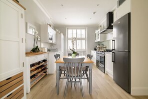 A kitchen with a dining table, chairs, a refrigerator, an oven, and a wine rack. - The Montagu 2 Bedroom With Terrace in Kensington (London)