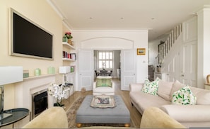 A living room with a fireplace, a television, a dining area, and a staircase. - The Montagu 2 Bedroom With Terrace in Kensington (London)