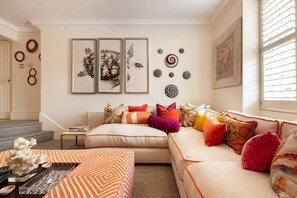 A living room with a sofa, a coffee table, and a staircase. - A Royal Residence Stylish 2 Bedroom in Kensington (London)