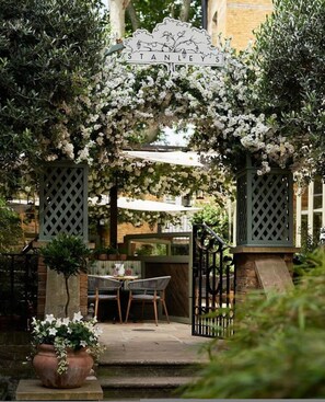 A garden entrance with a sign reading 'STANLEY'S' and a seating area with chairs and a table. - The Impressionist s Fireplace 4 BR Home in Chelsea (London)