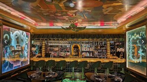 Un bar au décor asiatique traditionnel, avec une statue de dragon au centre, un plafond en bois et une variété de bouteilles et de verres exposés sur des étagères.