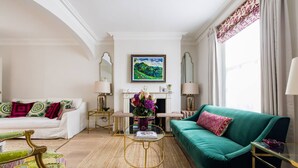 Un salon avec un canapé, des fauteuils, une cheminée et un tableau au mur.