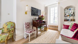 Une pièce comprenant un bureau, une chaise, un canapé, un téléviseur et une bibliothèque.