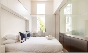 Ein modernes Hotelzimmer mit einem großen Bett, einem Schreibtisch und Blick auf die Stadt.