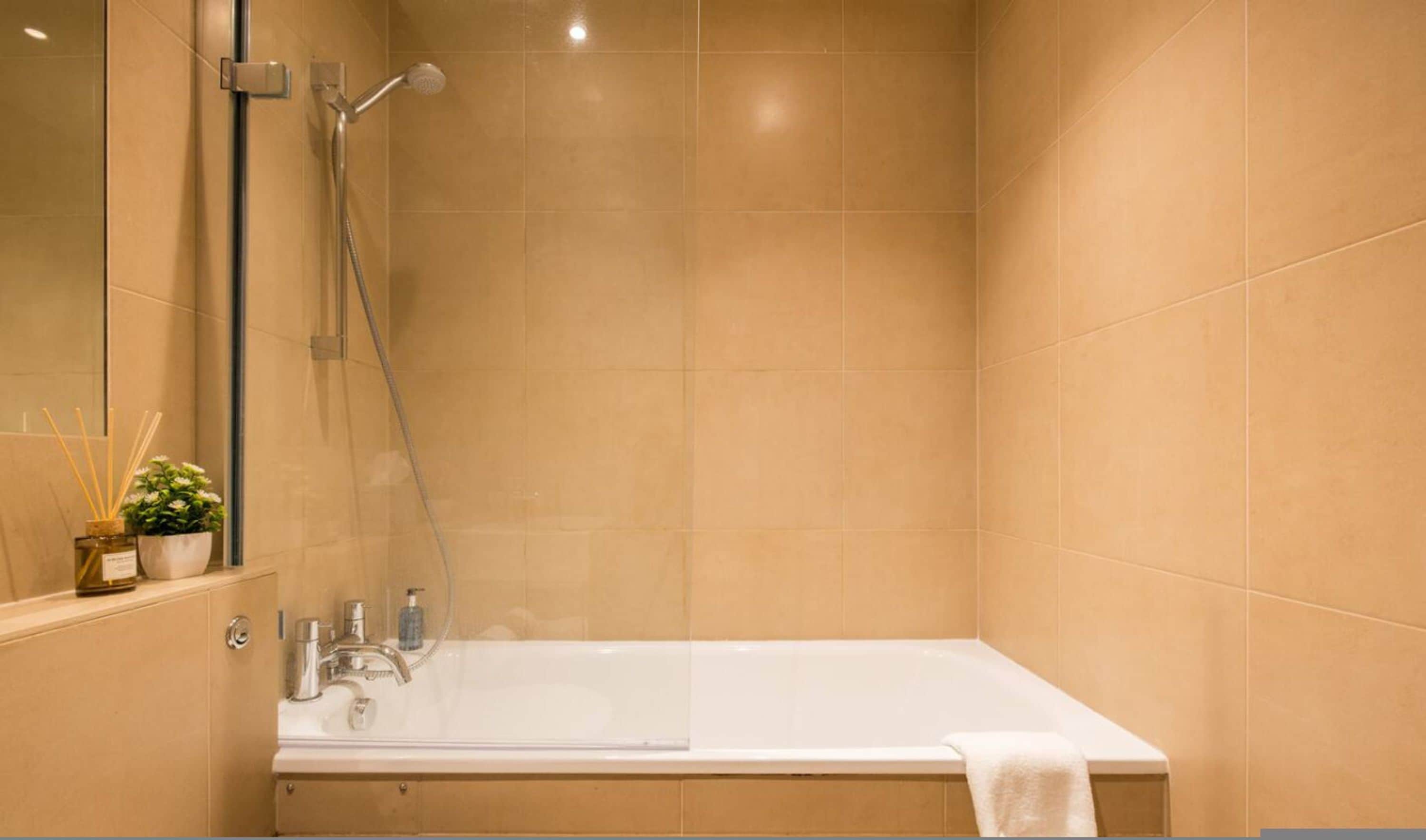 A bathroom with a bathtub, a shower, and a mirror.