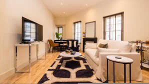 A spacious living area with a sofa, coffee table, TV, and dining setup. - London Muse 1 Bedroom Apartment in Belgravia (London)