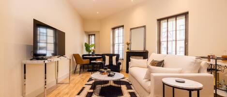 A spacious living area with a sofa, coffee table, TV, and dining setup.