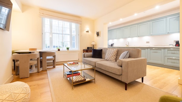Un salon moderne avec un canapé, une table basse et un coin repas avec des chaises.